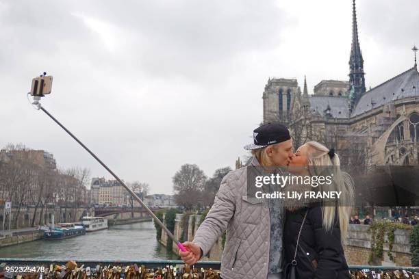 Couple d'amoureux sur un pont derrière la cathédrale Notre-Dame à Paris en France, en 2015.