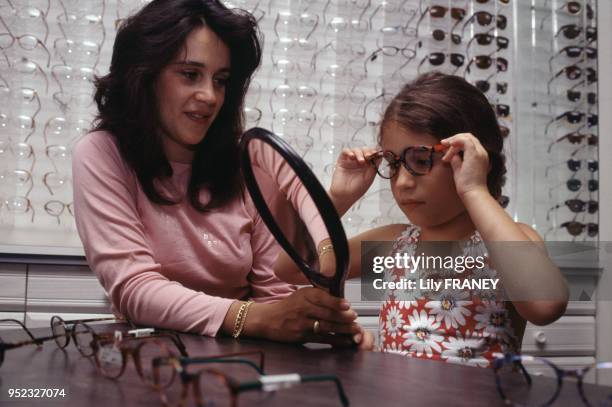 Opticienne faisant essayer des lunettes à une petite fille dans un centre de la ?Mutuelle Familiale? à Paris, en 1995, France.