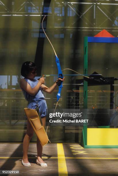 Petite fille faisant du tir à l'arc dans un centre de l'UCPA à Paris, le 8 août 1985, France.