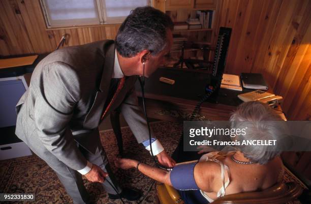 Médecin généraliste prenant la tension une patiente dans son cabinet à Paris, en 1995, France.