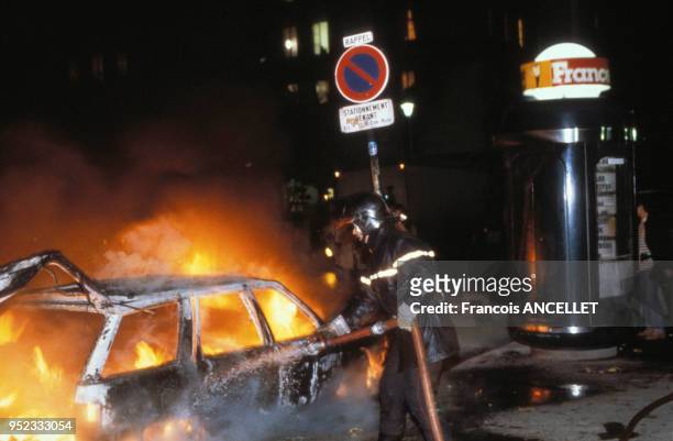 Pompier éteignant une voiture en feu lors d'une manifestation lycéenne à Paris, en novembre 1990, France.