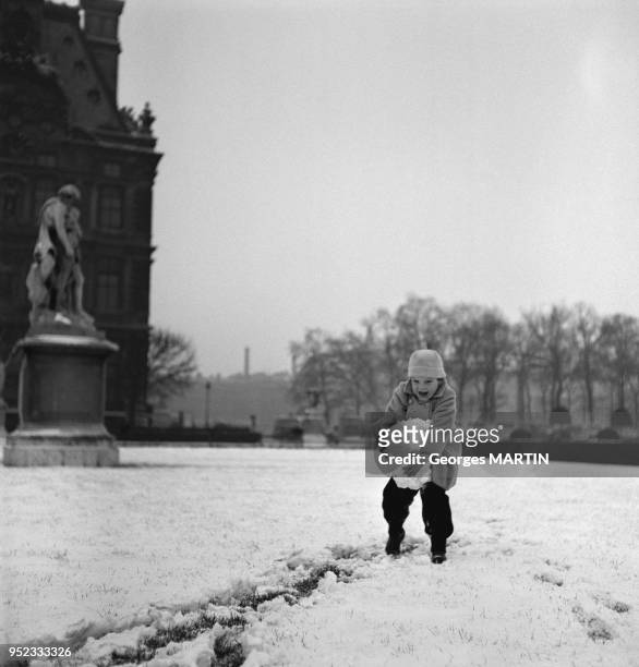 Enfant jouant dans la neige dans le Jardin des Tuileries, circa 1960 a Paris, France.