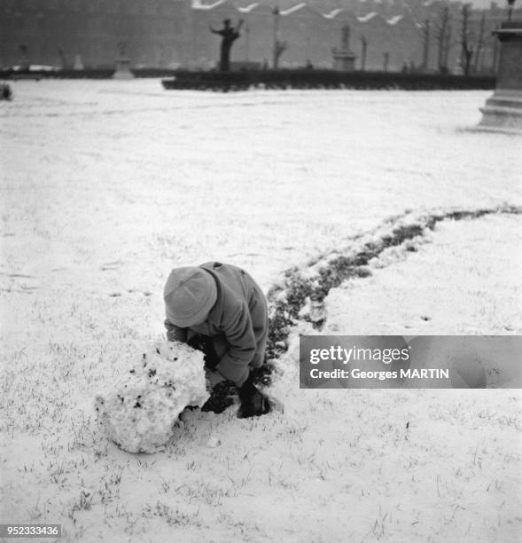 Enfant jouant dans la neige dans le Jardin des Tuileries, circa 1960 a Paris, France.