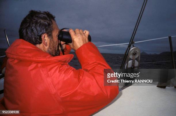 Eric Tabarly, sur le voilier Côte d'Or, observe la mer à la jumelle lors de la Whitbread ou Course autour du monde en mars 1986.