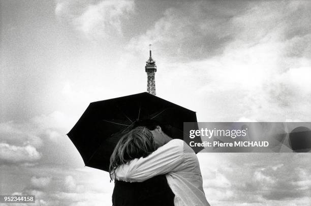Couple kissing under an umbrella near the Eiffel Tower. 20020000 Paris : Couple qui s'embrasse sous un parapluie à proximité de la Tour Eiffel...