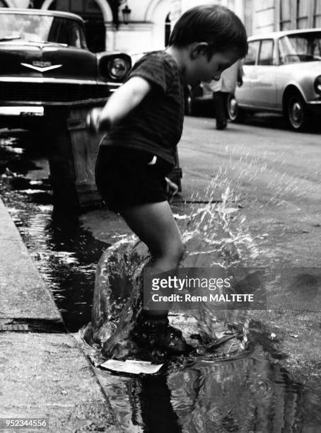 Enfant sautant dans une flaque d'eau à Paris, en France, en 1967.