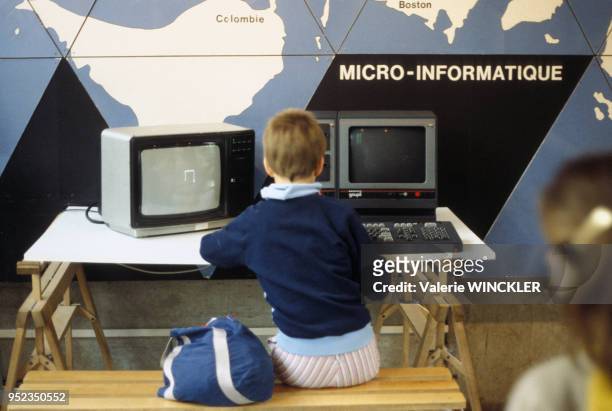 Enfant utilisant un ordinateur lors d'une exposition au Centre mondial informatique à Paris, circa 1980, France.