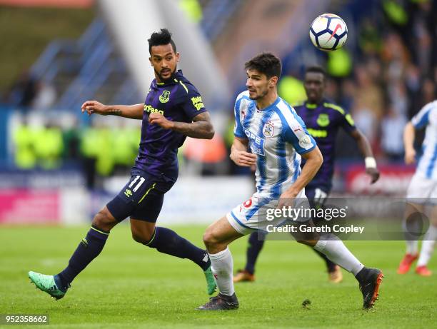 Theo Walcott of Everton competes for the ball with Christopher Schindler of Huddersfield Town during the Premier League match between Huddersfield...
