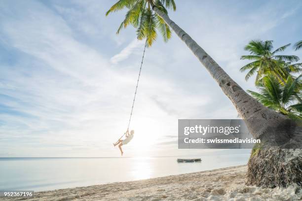 woman playing on swing rope, tropical climate palm trees in the philippines islands - siquijor islands stock pictures, royalty-free photos & images