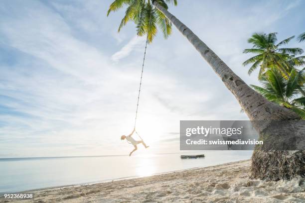 woman playing on swing rope, tropical climate palm trees in the philippines islands - siquijor islands stock pictures, royalty-free photos & images