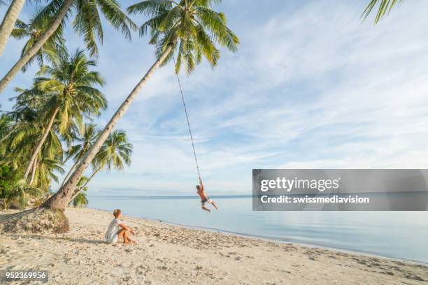 couple playing on beach, swing rope on palm tree in tropical island asia - couple swinging stock pictures, royalty-free photos & images