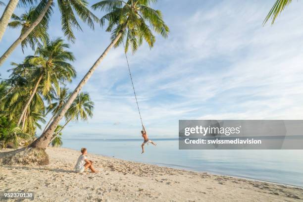 couple playing on beach, swing rope on palm tree in tropical island asia - island of siquijor stock pictures, royalty-free photos & images