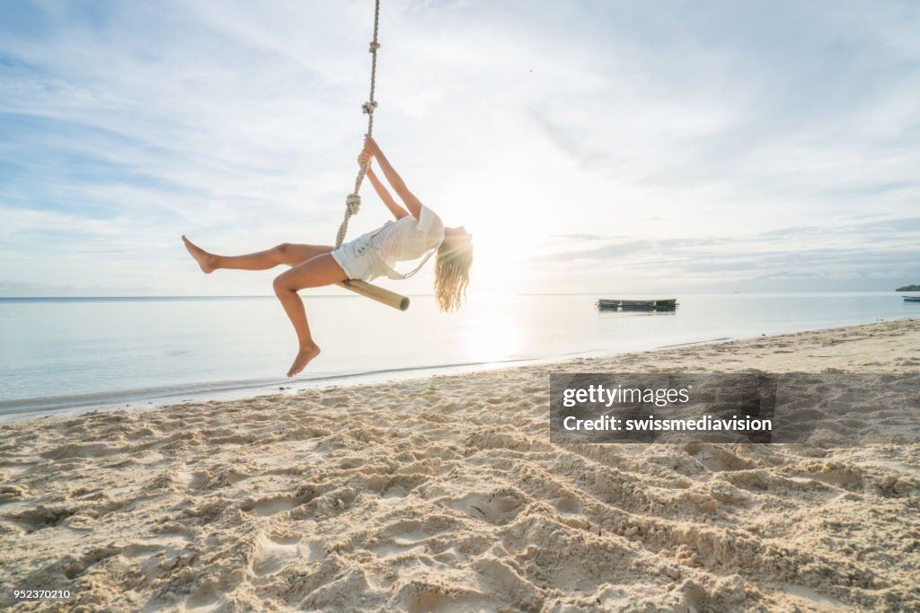 Mujer tocando en cuerdas del columpio, palmeras de clima tropical en las Islas Filipinas