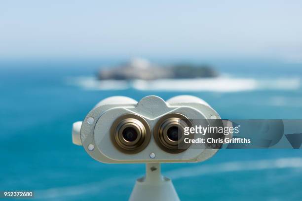 binoculars looking out on to a view of mouro island and lighthouse - telescopes stock pictures, royalty-free photos & images