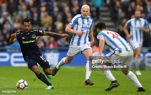 Aaron Mooy and Christopher Schindler of Huddersfield Town put pressure on Theo Walcott of Everton during the Premier League match between...