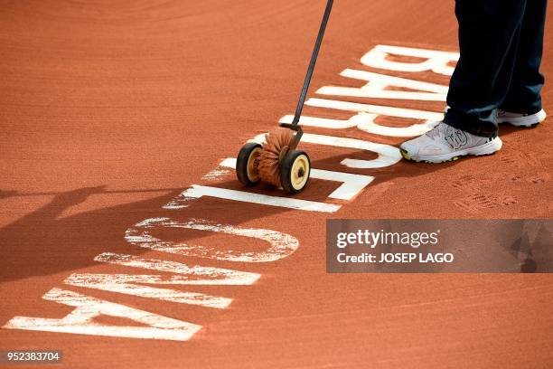 Worker cleans the tennis court ground during the Barcelona Open ATP tennis tournament semi-finals in Barcelona on April 28, 2018.