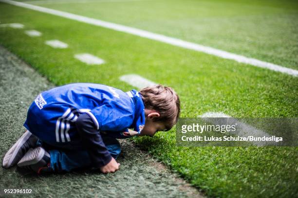 Young fan touches the gras of the pitch prior to the Bundesliga match between FC Schalke 04 and Borussia Moenchengladbach at Veltins-Arena on April...