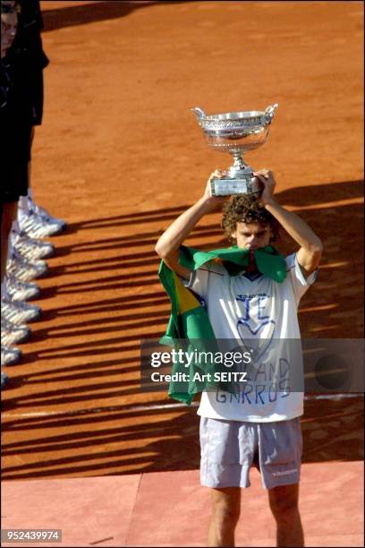 Paris, france, june l0, 2001 at roland garros, 2001 french open champion guga kuerten holds the men's singles trophy over his head and the brazilian...