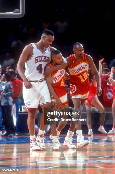 Rick Mahorn of the Philadelphia 76ers talks and hugs Spud Webb and Sidney Moncrief of the Atlanta Hawks during an NBA game on February 27, 1991 at...
