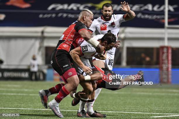 Lyon's Australian fly-half Michael Harris is tackled by Oyonnax' Australian fullback Ulupano Seuteni and Oyonnax' New-Zealander hooker Hikawera...