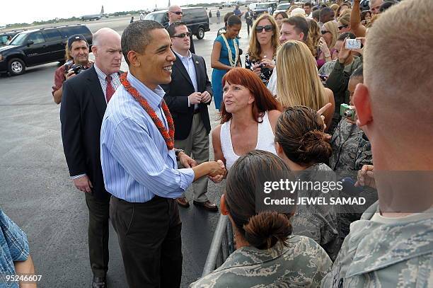 President Barack Obama and First Lady Michelle Obama greet people upon their arrival at the Hickam Air Force Base in Honolulu, Hawaii, on December...