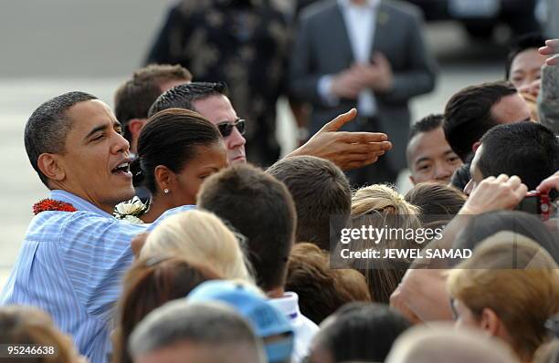 President Barack Obama and First Lady Michelle Obama greet people upon their arrival at the Hickam Air Force Base in Honolulu, Hawaii, on December...