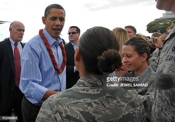 President Barack Obama and First Lady Michelle Obama greet people upon their arrival at the Hickam Air Force Base in Honolulu, Hawaii, on December...