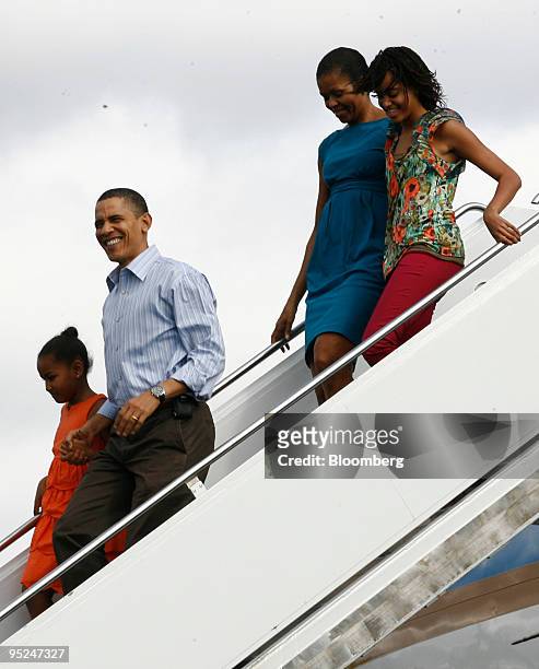 President Barack Obama, second from left, disembarks Air Force One with his daughter Sasha, left, wife Michelle, right, and daughter Malia, at Hickam...