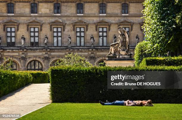 Des gens profitant du soleil dans le Jardin des Tuileries le 12 Juillet 2013, Pavillon de Flore dans le Musee du Louvre, Paris, France.