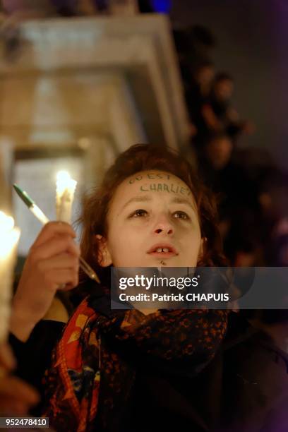 Jeune fille tenant une bougie et un stylo lors d'un rassemblement de citoyens pour soutenir le journal 'Charlie Hebdo' suite à l'attaque terroriste...