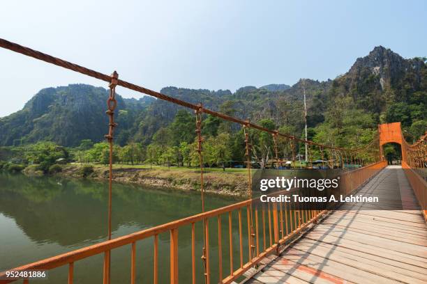 suspension bridge and mountainous landscape in vang vieng - nam song river stock pictures, royalty-free photos & images