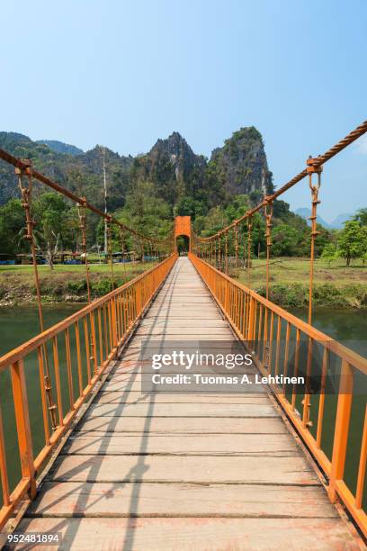 suspension bridge and mountainous landscape in vang vieng - nam song river stock pictures, royalty-free photos & images