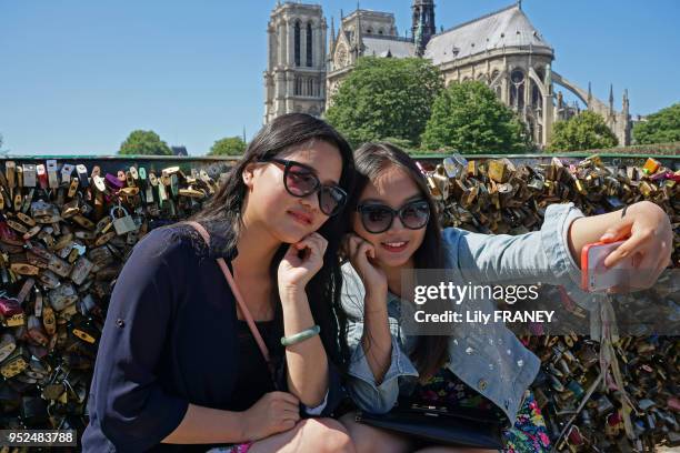 Jeunes femmes se faisant un selfie sur le pont de l'Archevéché, juin 2015, Paris, France.