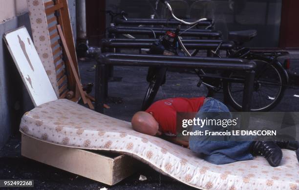 Homeless man in Paris is sleeping on a discarded mattress amid other discarded items in the 18th district of Paris near Pigalle, 2008 in Paris,...