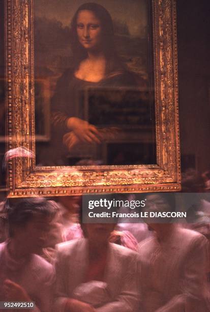 The famous Mona Lisa at the Louvre Museum with a group of Japanese tourists being reflected on the large glass that protects the painting, 1987 in...