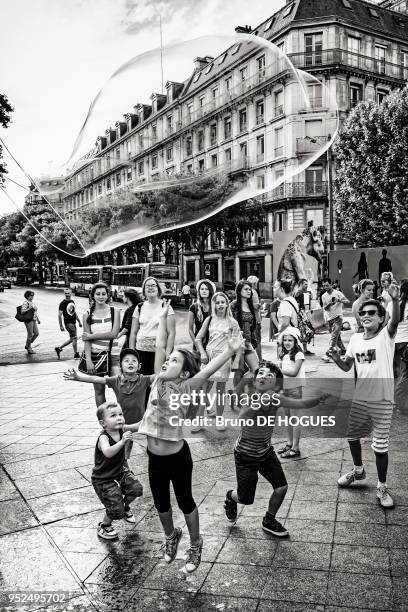 Des enfants voulant attraper une bulle de savon sur le parvis de l'Hôtel de Ville pendant Paris-Plages 2015, Paris, France.
