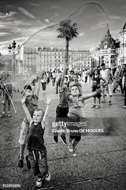 Des enfants voulant attraper une bulle de savon sur le parvis de l'Hôtel de Ville pendant Paris-Plages 2015, Paris, France.