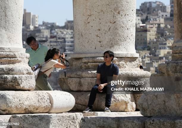 Tourists pose for a photo in the Temple of Hercules, a Roman temple that was built in 162-66 AD, as they visit the Amman Citadel in the Jordanian...