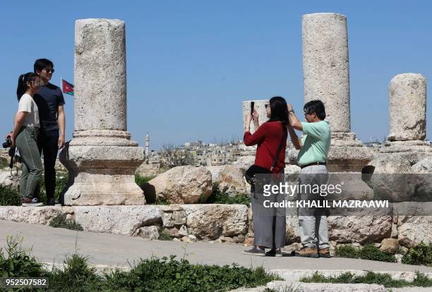 Tourists pose for a photo as they visit the Amman Citadel in the Jordanian capital on March 13, 2018. - With its rock-hewn ancient city of Petra,...