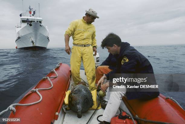 Luc Long inspecting an amphora. Luc Long regardant une amphore qui vient d'être remontée, le navire du DRASSM « l'archéonaute » à l'arrière plan.