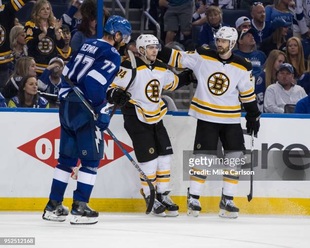 Victor Hedman of the Tampa Bay Lightning skates to the bench after giving up a goal as Jake DeBrusk and Adam McQuaid of the Boston Bruins celebrate...