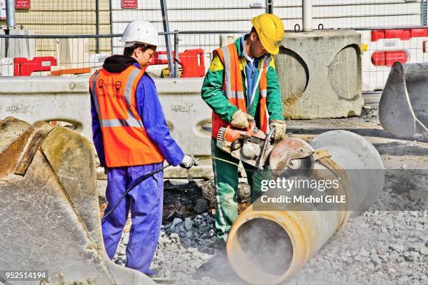 Ouvrier sciant un tuyau en ciment d'une canalisation, 2 avril 2013, Le Mans, France.