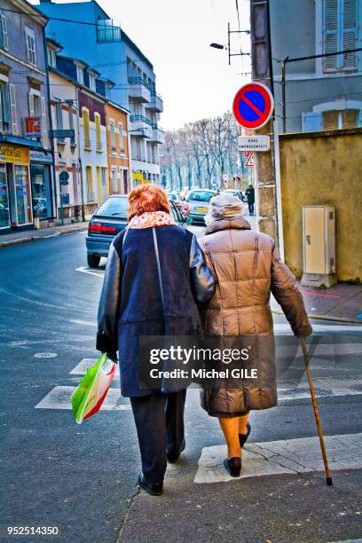 Femme qui donne le bras un une femme agee avec une canne, Le Mans, France.