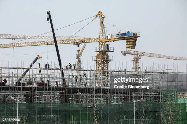 Cranes operate at residential buildings under construction at the Dalian Wanda Group Co. Oriental Movie Metropolis film production hub in Qingdao,...