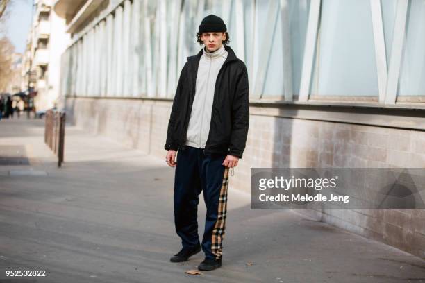 Model Gautier wears a black beanie black jacket, white jacket, and Burberry tartan joggers after the Lacoste show on February 28, 2018 in Paris,...