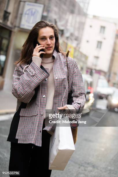 French model Othilia Simon talks on the phone and wears a red gingham jacket with pockets after the Carven show on March 1, 2018 in Paris, France.