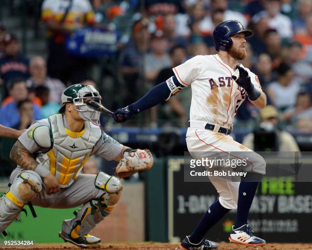 Derek Fisher of the Houston Astros hits a two-run home run in the fourth inning as Bruce Maxwell of the Oakland Athletics looks on at Minute Maid...