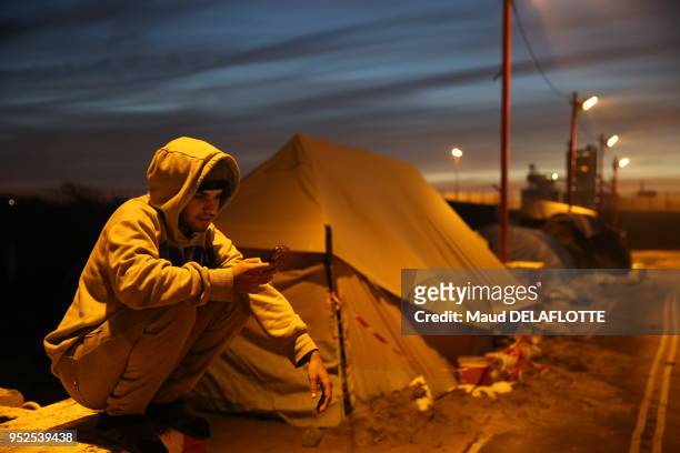 Un jeune réfugié consultant son téléphone portable dans le camp appelé 'jungle' de Calais le 7 décembre 2015, France.