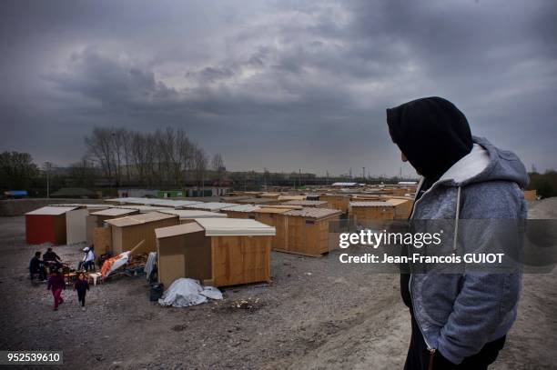 Migrant consultant son téléphone portable le 11 avril 2016 dans le camp de réfugiés de Grande-Synthe en banlieue de Dunkerque, France.