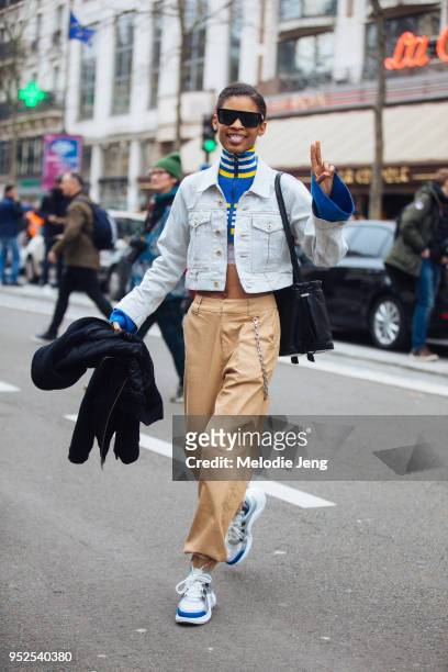 Model Theresa Hayes sticks out her tongue and gestures a peace sign while wearing black Victoria Beckham sunglasses, cropped Carven light wash denim...